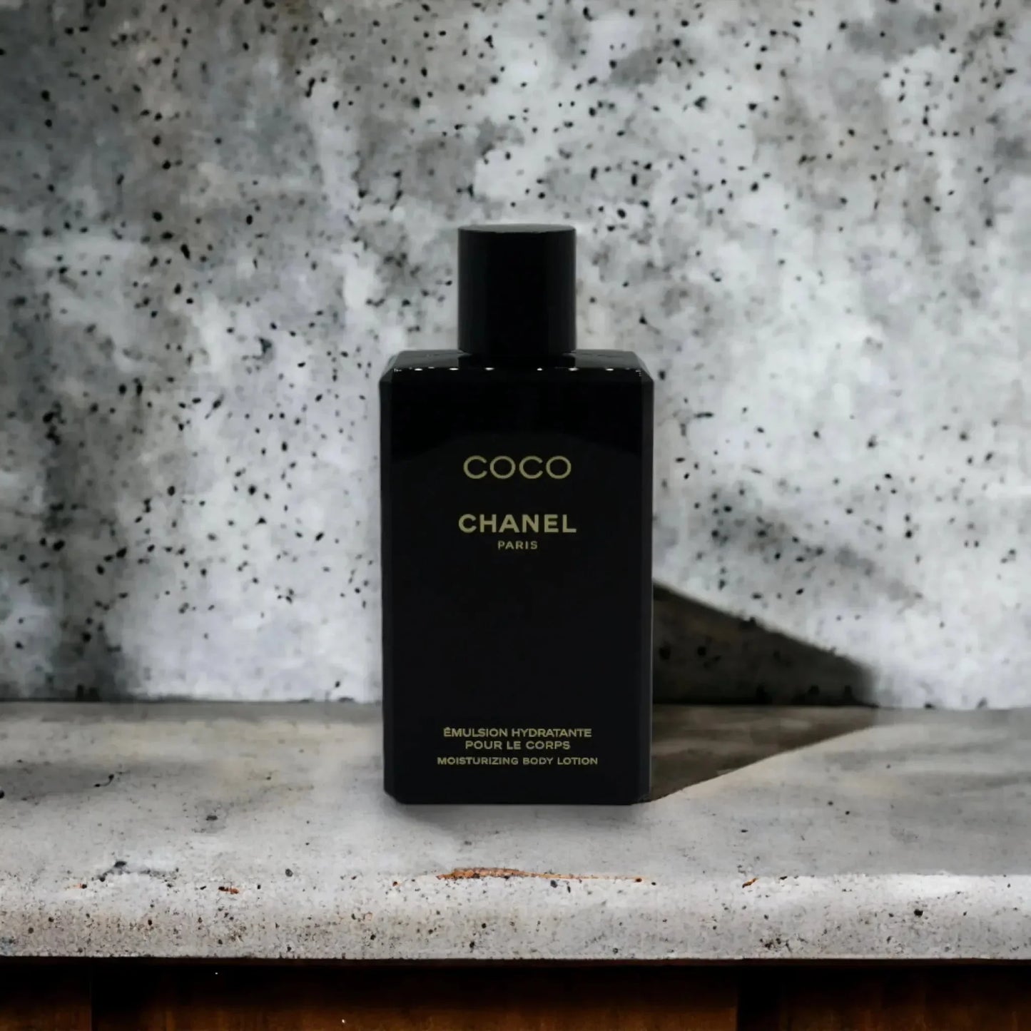 Schwarze Flasche Coco Chanel feuchtigkeitsspendende Bodylotion vor grauem Hintergrund