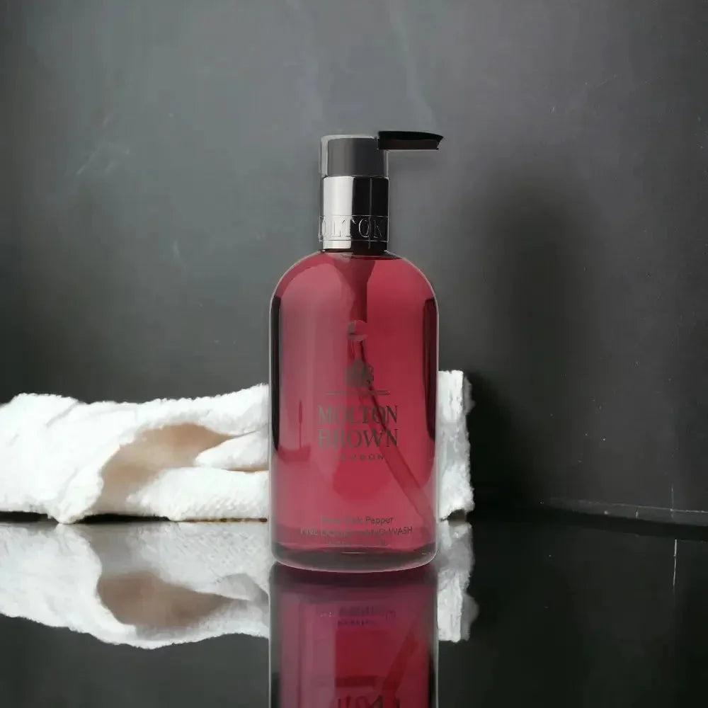 Rosa Handseife im Pumpspender vor dunklem Hintergrund, reflektierend, mit weißem Handtuch