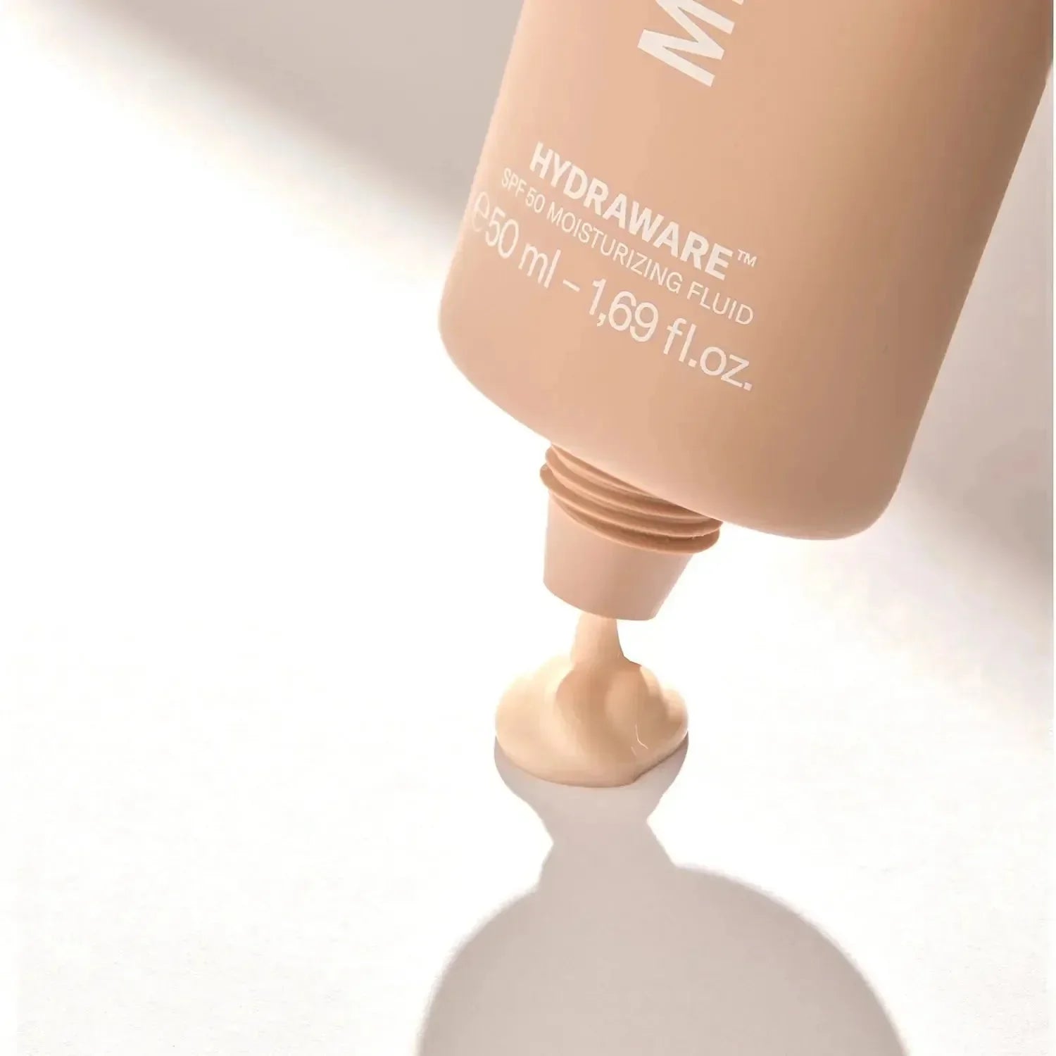 Beige Tube Hydraware SPF 50 Feuchtigkeitsfluid, Creme wird ausgedrückt auf weißer Fläche
