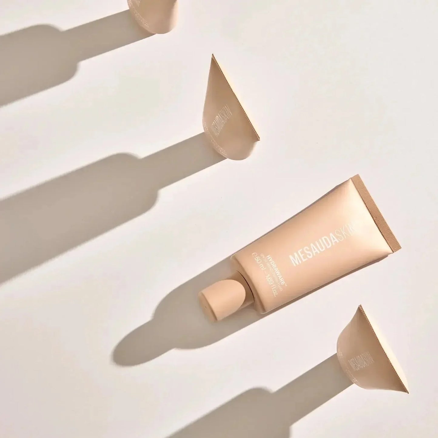 Beigefarbene Tube Mesaudaskin Fluid SPF 50 Moisturizer mit Schatten auf hellem Hintergrund