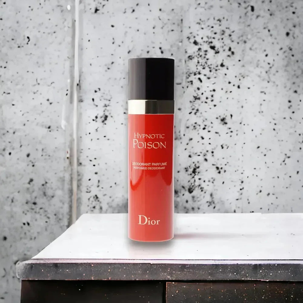 Roter Hypnotic Poison Deodorant Spray auf Tisch vor grauer Wand, luxuriöses Damenparfum