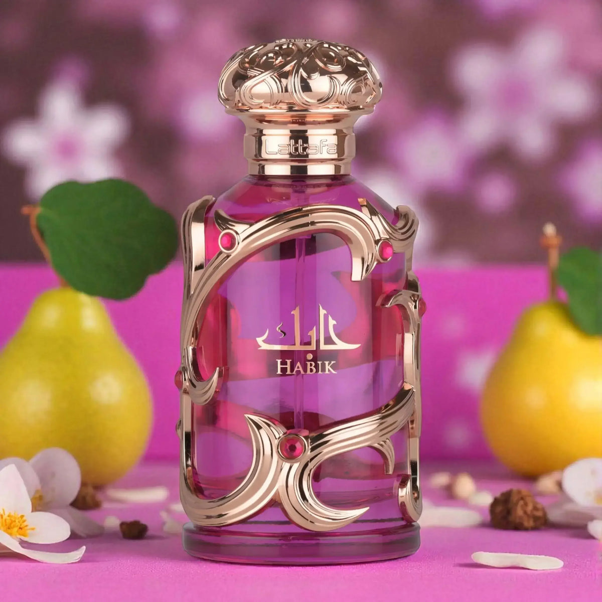 Luxus Damenparfum Flakon mit goldenen Verzierungen auf pinkem Hintergrund, Blumen und Birnen