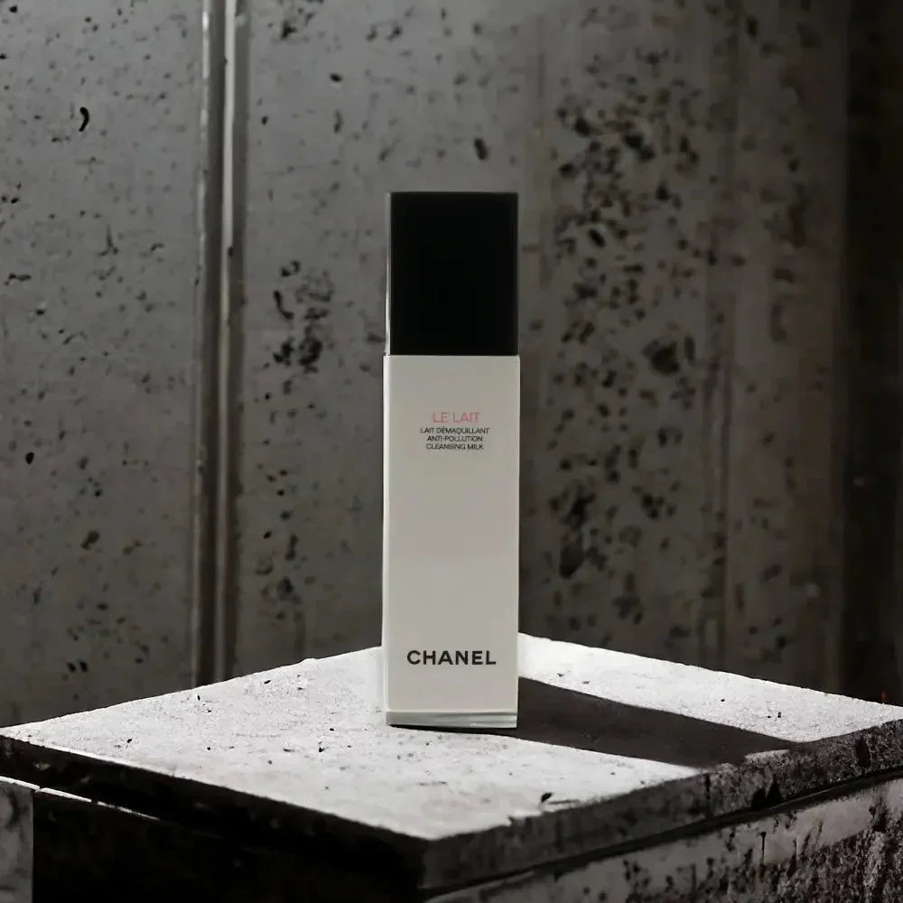 Reinigungsmilch in weißer Flasche mit schwarzem Deckel auf Steinuntergrund vor grauer Wand