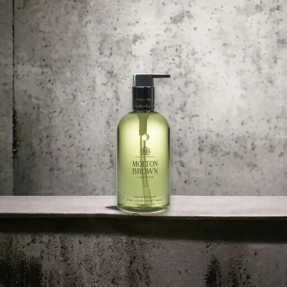 Molton Brown Lime Patchouli Handseife im transparenten Spender vor grauer Wand