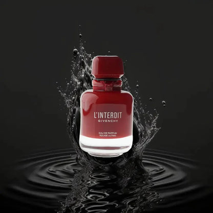 Rotes Parfum L'Interdit Eau de Parfum in elegantem Flakon mit Wasserspritzer auf schwarzem Hintergrund
