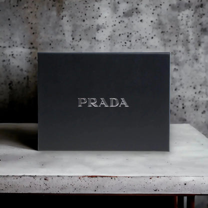 Elegante schwarze Geschenkbox mit silbernem PRADA-Logo auf Marmorfläche, Luxus Parfumset