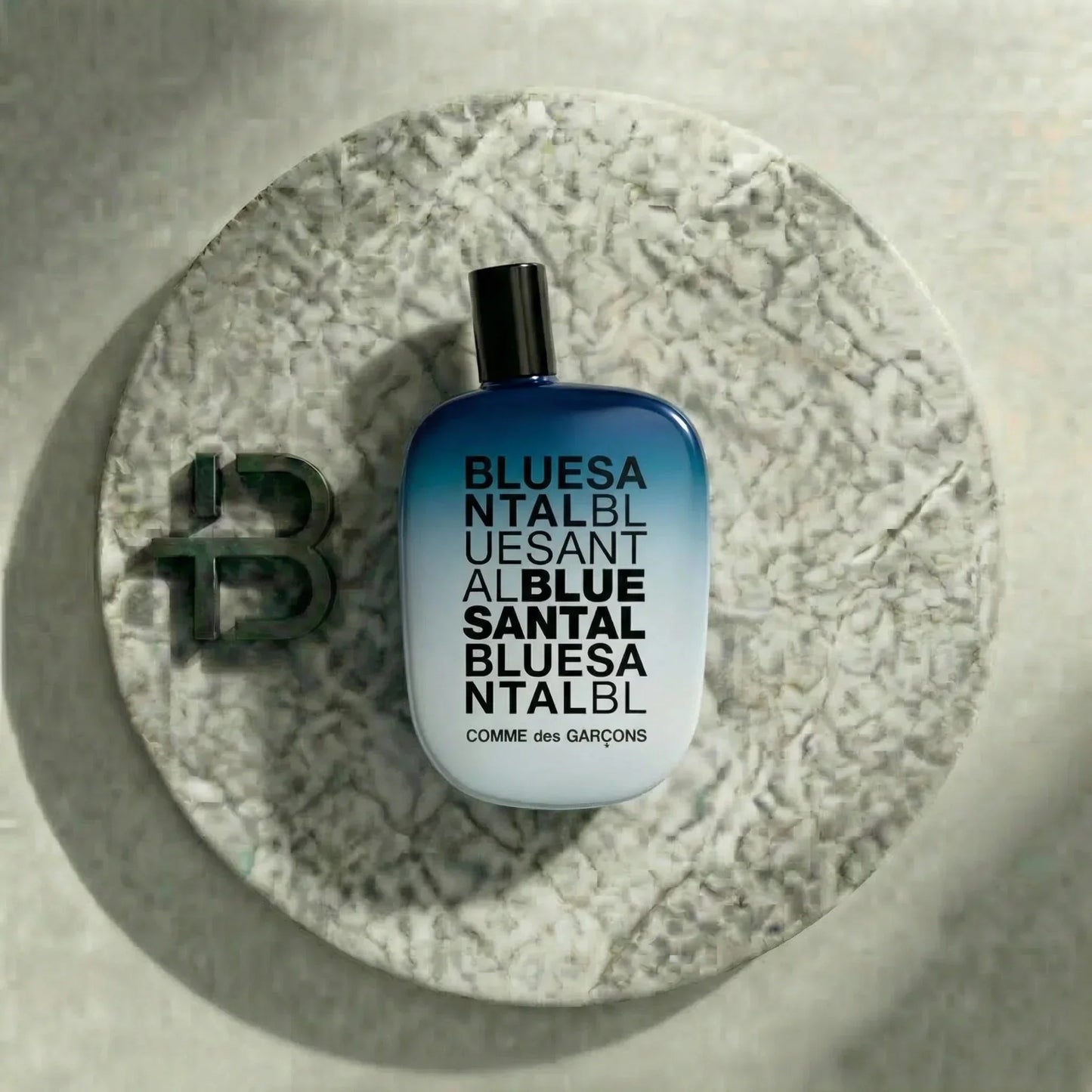 Blauer Comme des Garçons Duftflakon BLUE SANTAL auf rundem Steinteller, stilvolle Parfumpräsentation