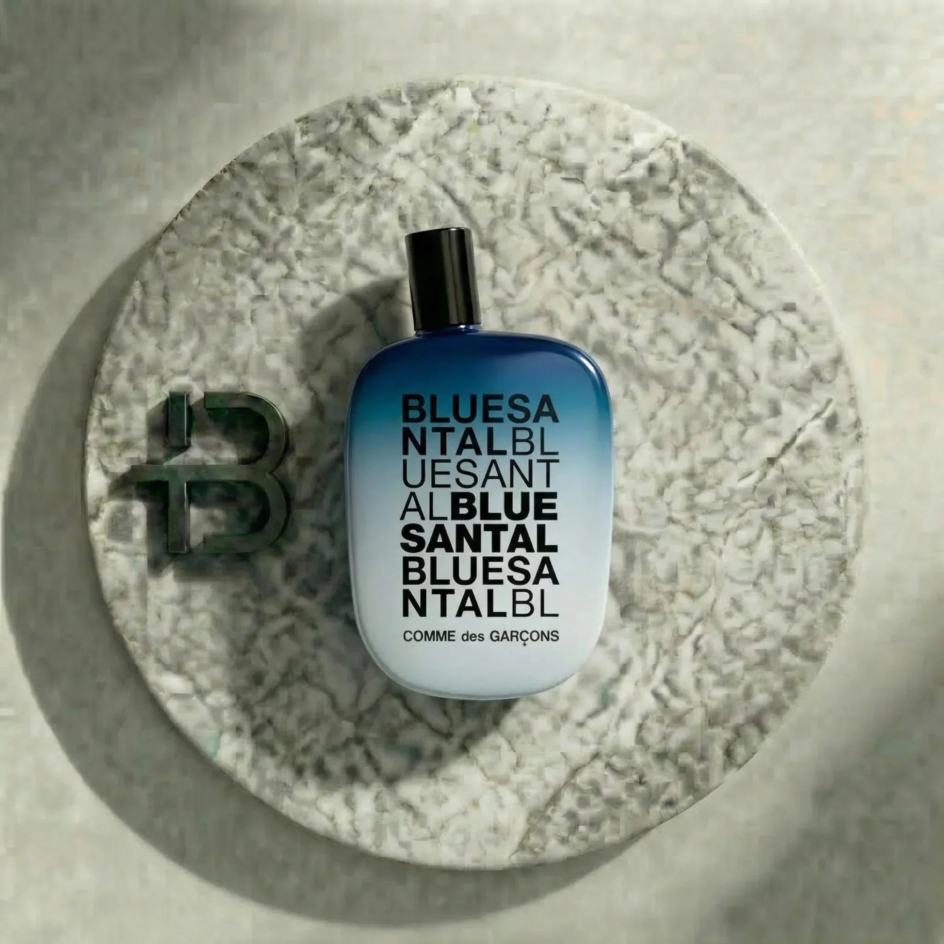 Blauer Comme des Garçons Duftflakon BLUE SANTAL auf rundem Steinteller, stilvolle Parfumpräsentation