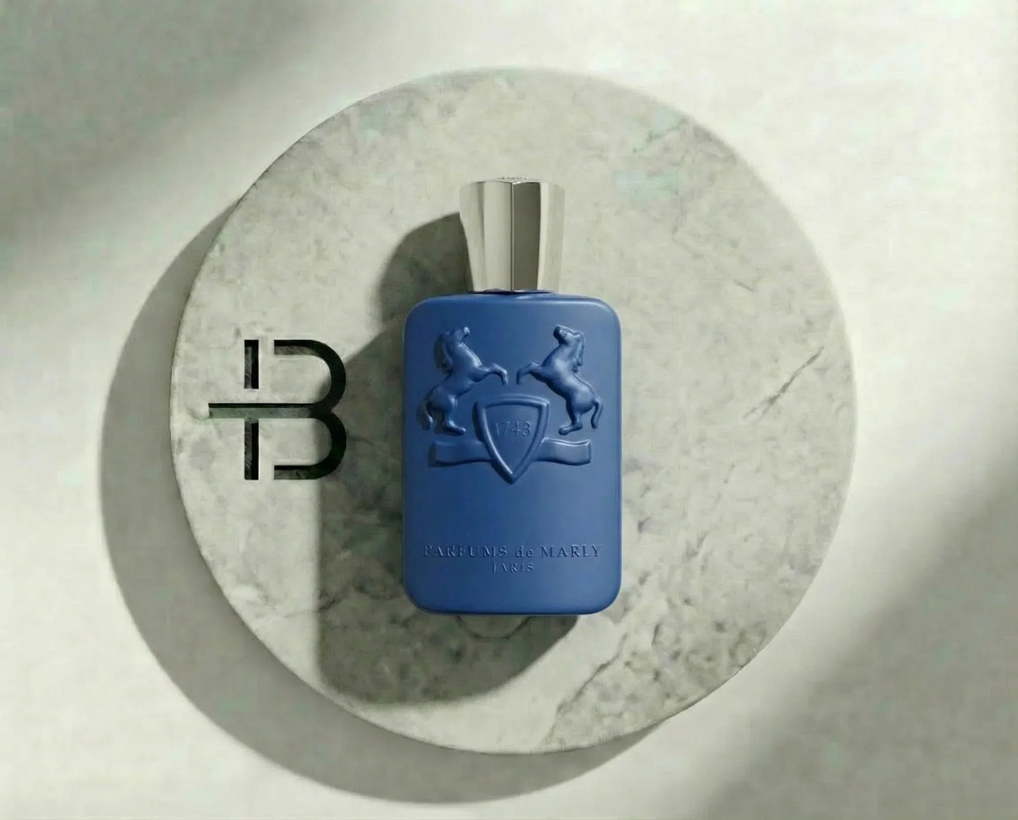 Luxusparfum in blauer Flasche mit silbernem Verschluss auf rundem Marmortablett, eleganter Hintergrund