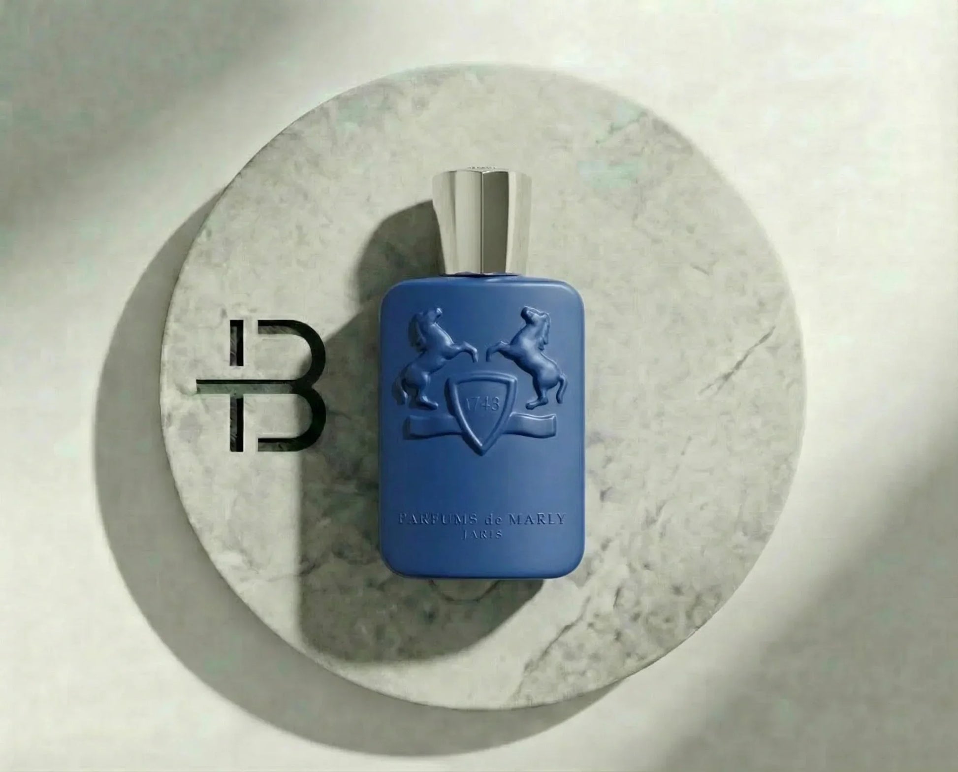 Luxusparfum in blauer Flasche mit silbernem Verschluss auf rundem Marmortablett, eleganter Hintergrund