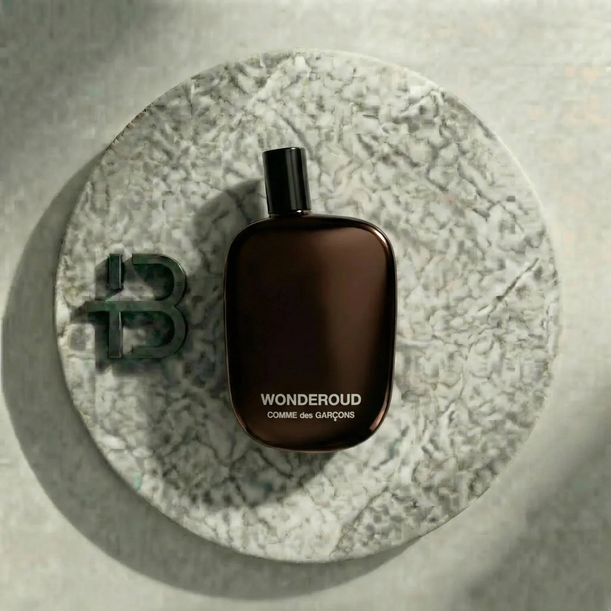 Braunes Parfumflakon WONDEROUD Comme des Garçons auf rundem Marmortablett, edles Design, Luxusduft