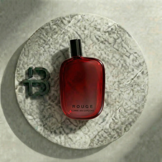 Rotes Parfümflakon Rouge Comme des Garçons auf rundem Marmortablett, luxuriöses Damenparfum