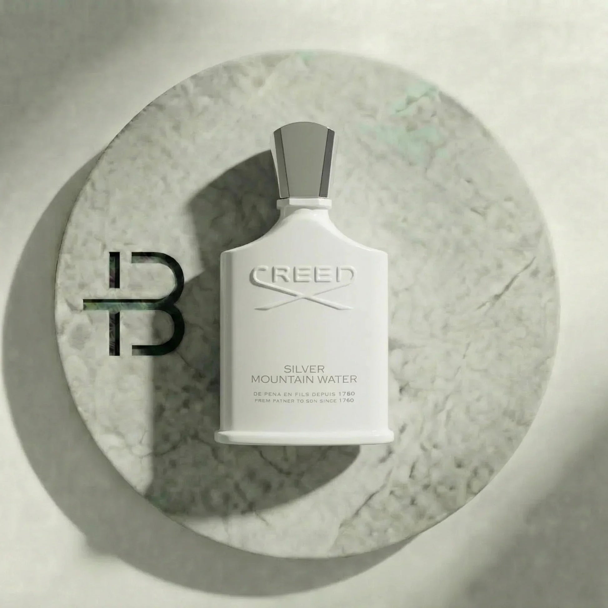 Weißer Flakon Parfum Silver Mountain Water auf rundem Marmorsockel, luxuriöses Design