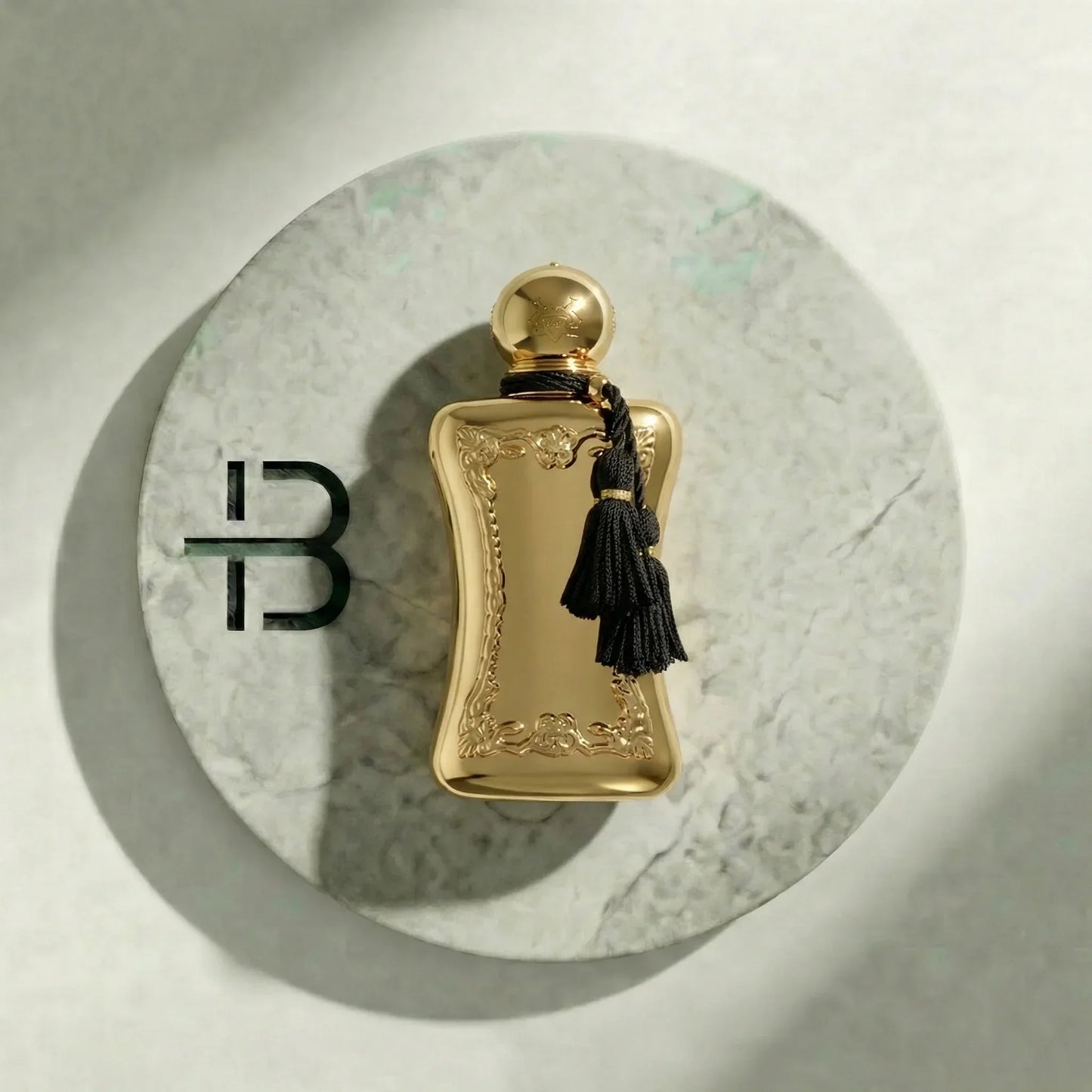 Goldenes Luxusparfum für Damen und Herren auf Marmorteller mit schwarzer Quaste.