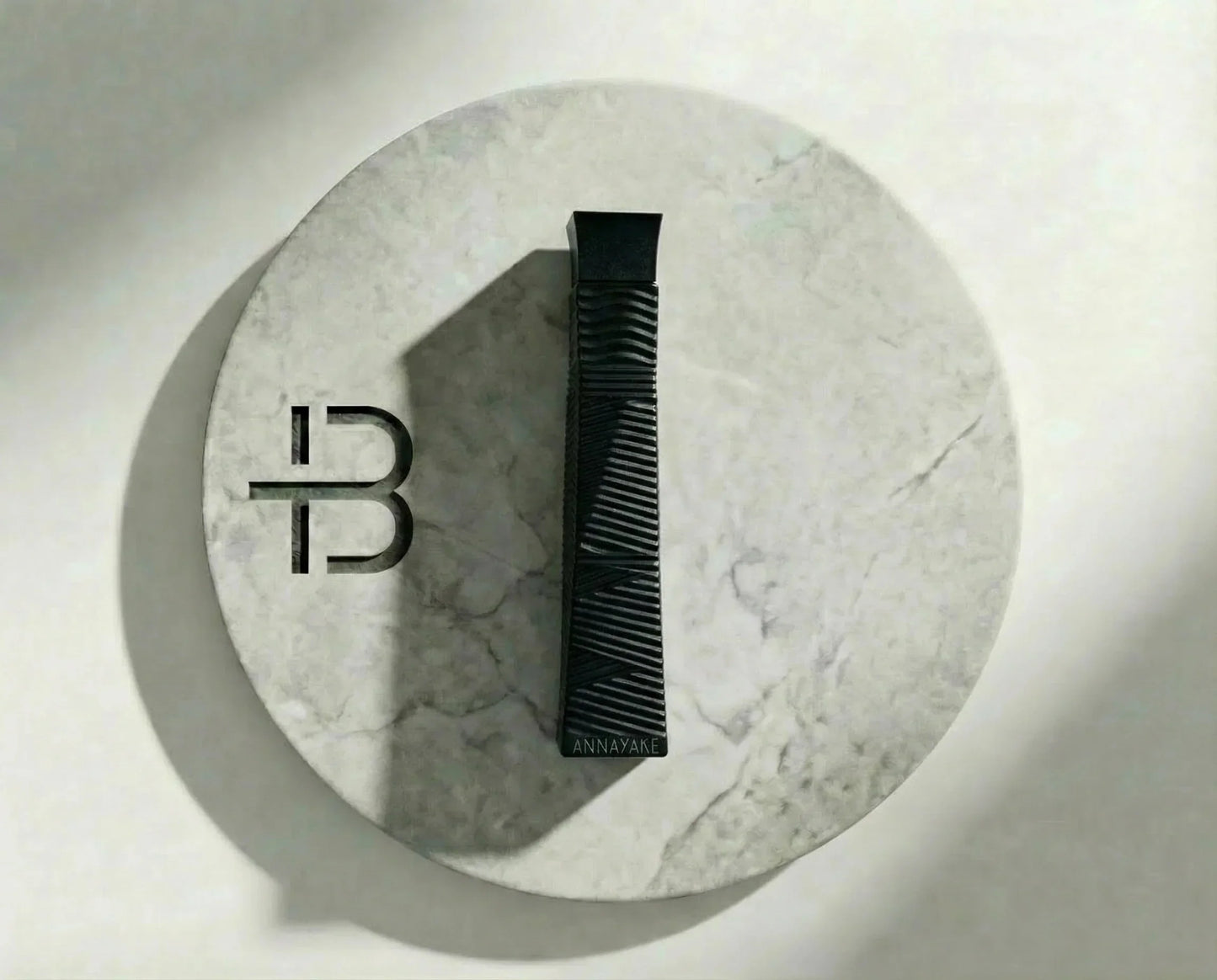 Schwarzer Parfumflakon mit elegantem Design auf rundem Marmor-Tablett, luxuriöses Duftprodukt.