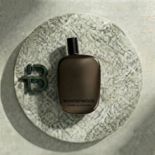 Brauner Parfumflakon Wonderwood Comme des Garçons auf rundem Marmortablett