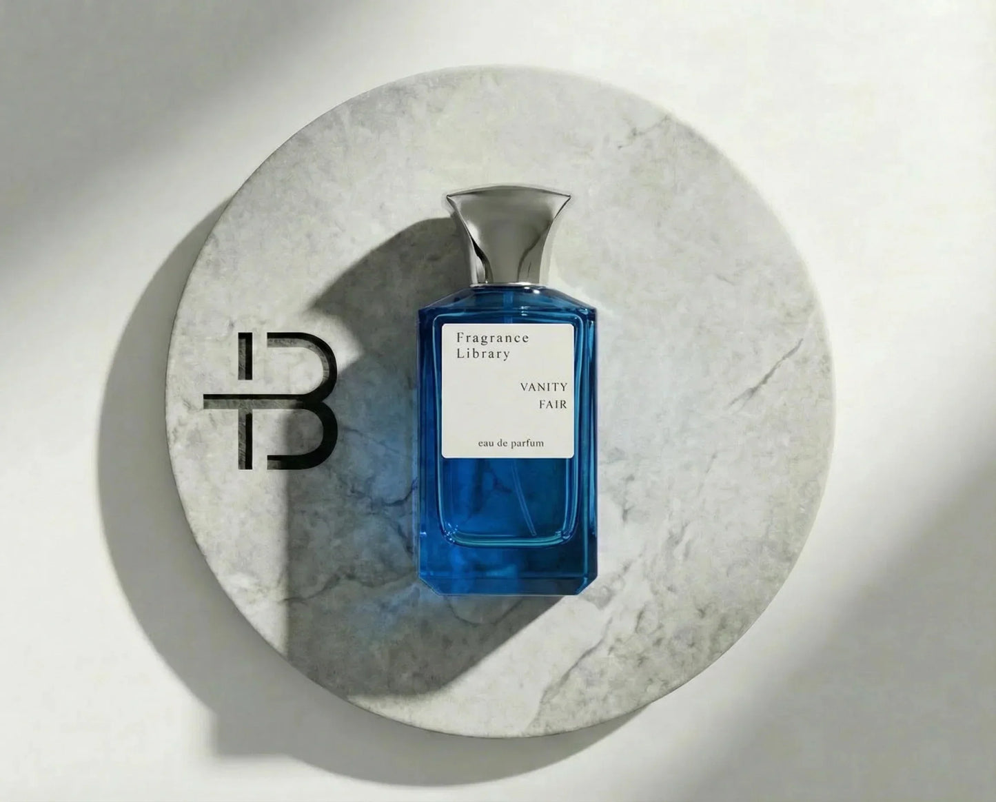 Blauer Parfumflakon Vanity Fair Fragrance Library auf rundem Marmortablett, luxuriöser Duft