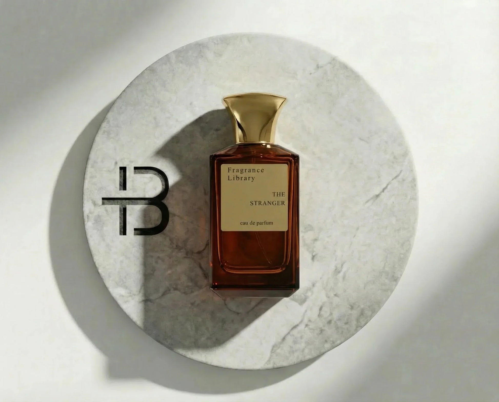 Luxusparfum Flakon mit goldener Kappe auf Marmorteller, Parfüm The Stranger