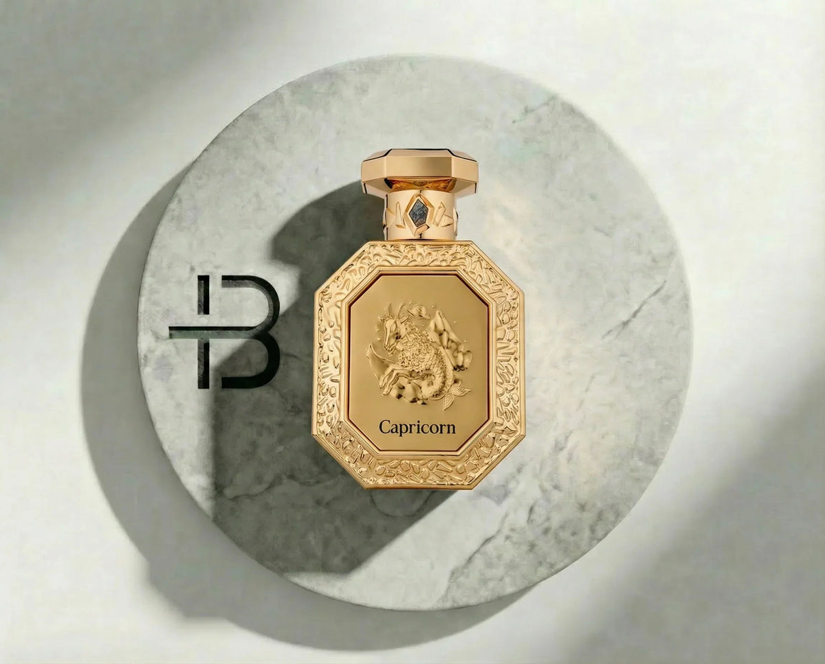 Goldener French Avenue Capricorn Parfumflakon mit Drachenrelief auf Marmoruntergrund.