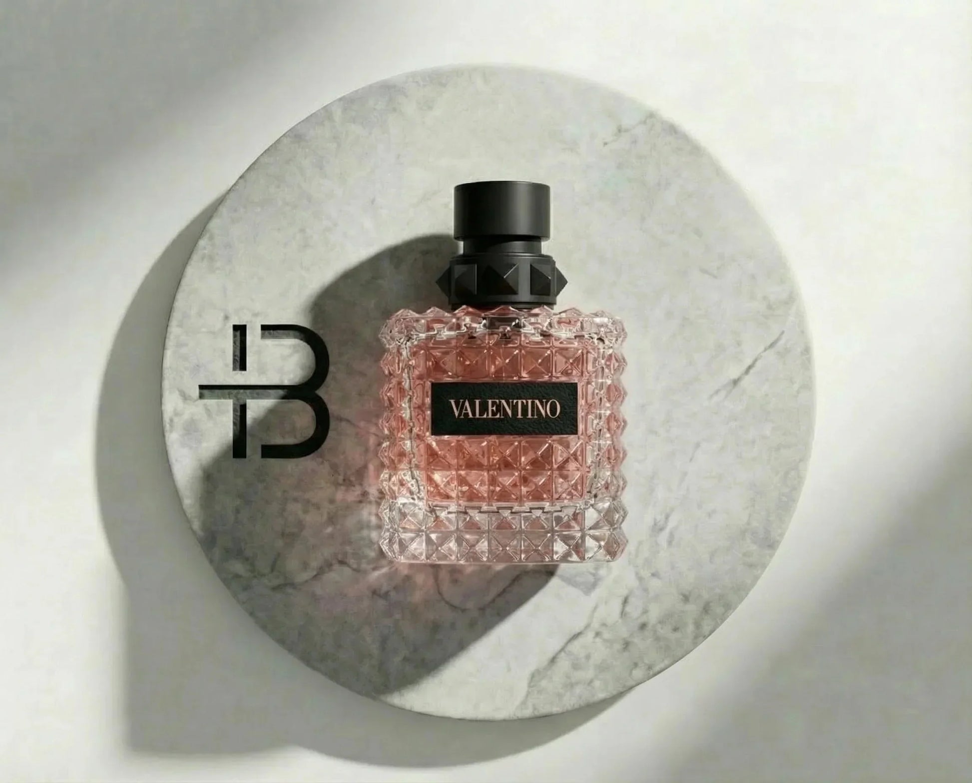 Luxuriöses Parfum für Damen in edlem Glasflakon mit roséfarbenem Duft auf Mamorplatte
