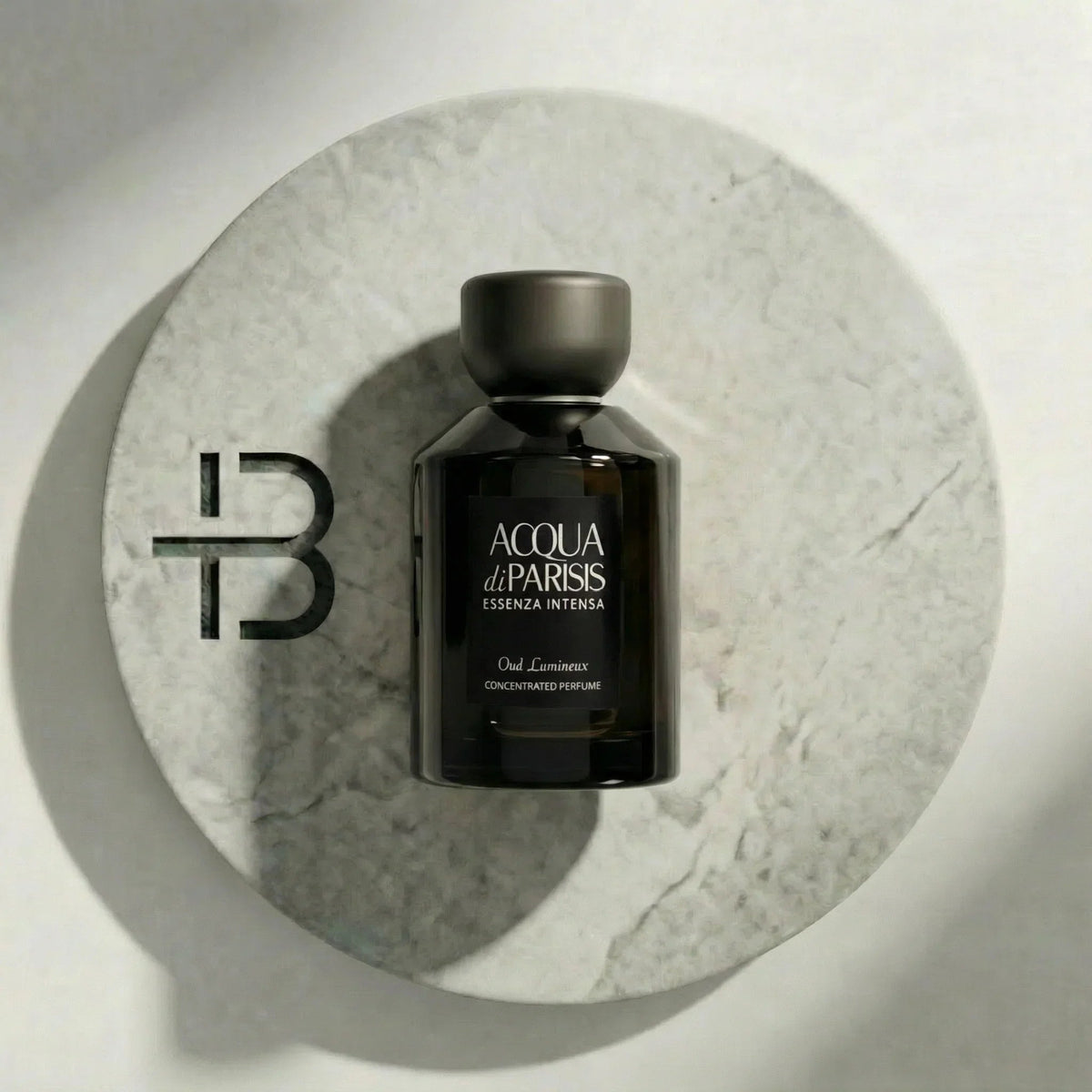 Reyane Tradition Acqua di Parisis Essenza Intensa Oud Lumineux Parfumflakon auf Marmoruntergrund.