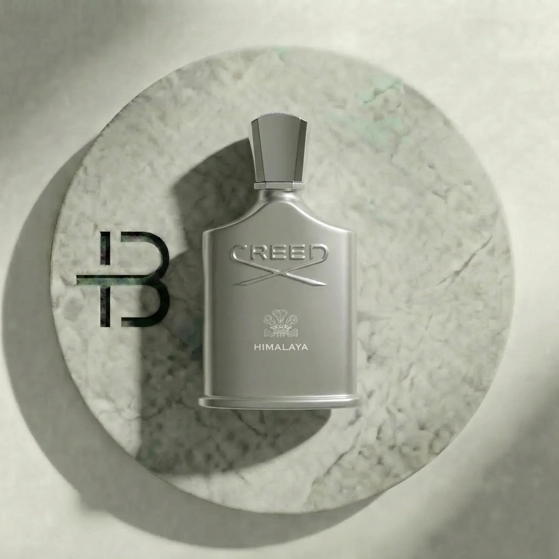 Silbernes Creed Himalaya Parfumflakon für Herren auf rundem Marmortablett, edles Luxusparfum