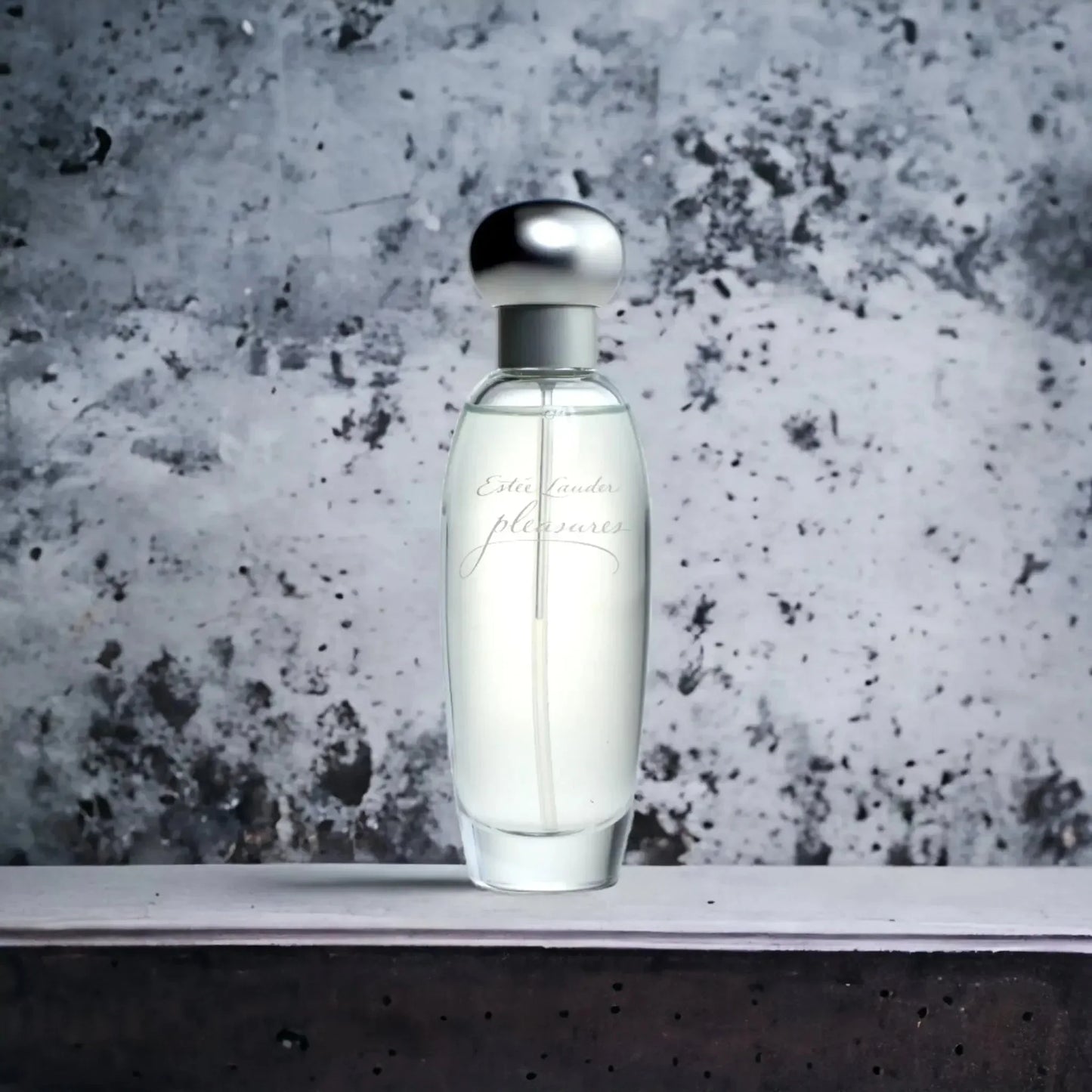 Eleganter Flakon eines Damenparfums mit silbernem Verschluss vor grauem Hintergrund