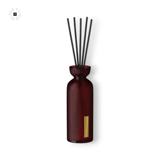 Eleganter Raumduft Diffusor in einer geriffelten, dunkelroten Glasflasche mit schwarzen Stäbchen.