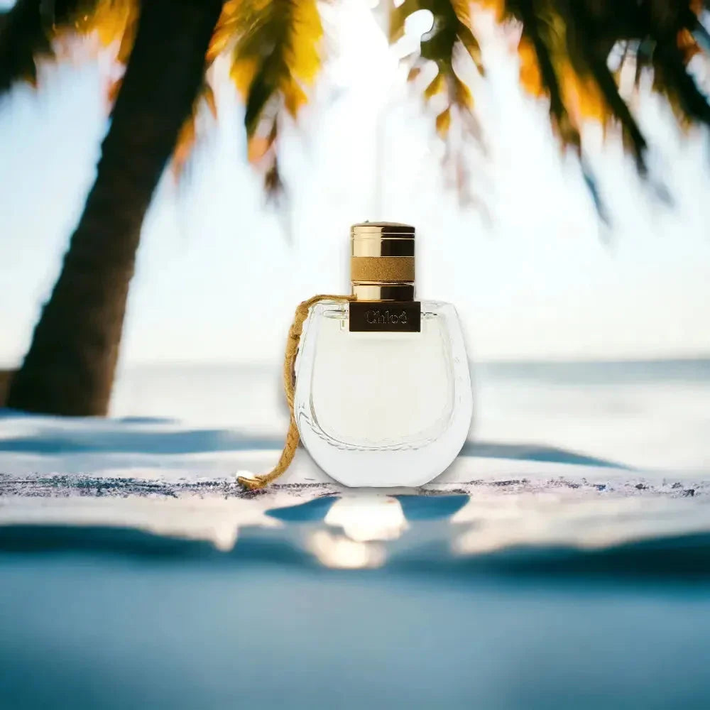 Luxus Damenparfum-Flakon mit goldenen Akzenten am Strand unter Palmen in Sonnenlicht
