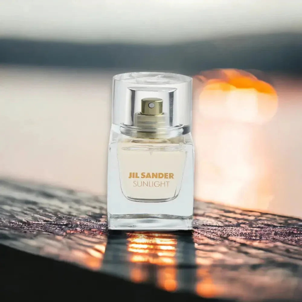 Jil Sander Sunlight Eau de Parfum Flakon auf reflektierender Oberfläche vor Sonnenuntergang