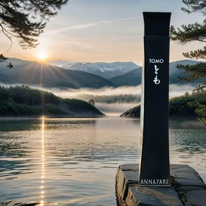 Annayake Tomo Eau de Toilette Flakon vor natürlicher See- und Bergkulisse bei Sonnenaufgang
